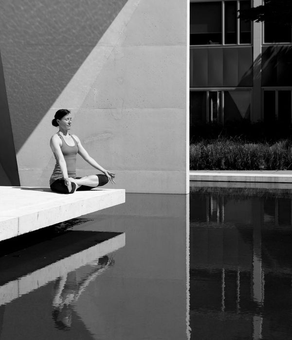 Woman in a calm, seated yoga pose in a minimalist setting.